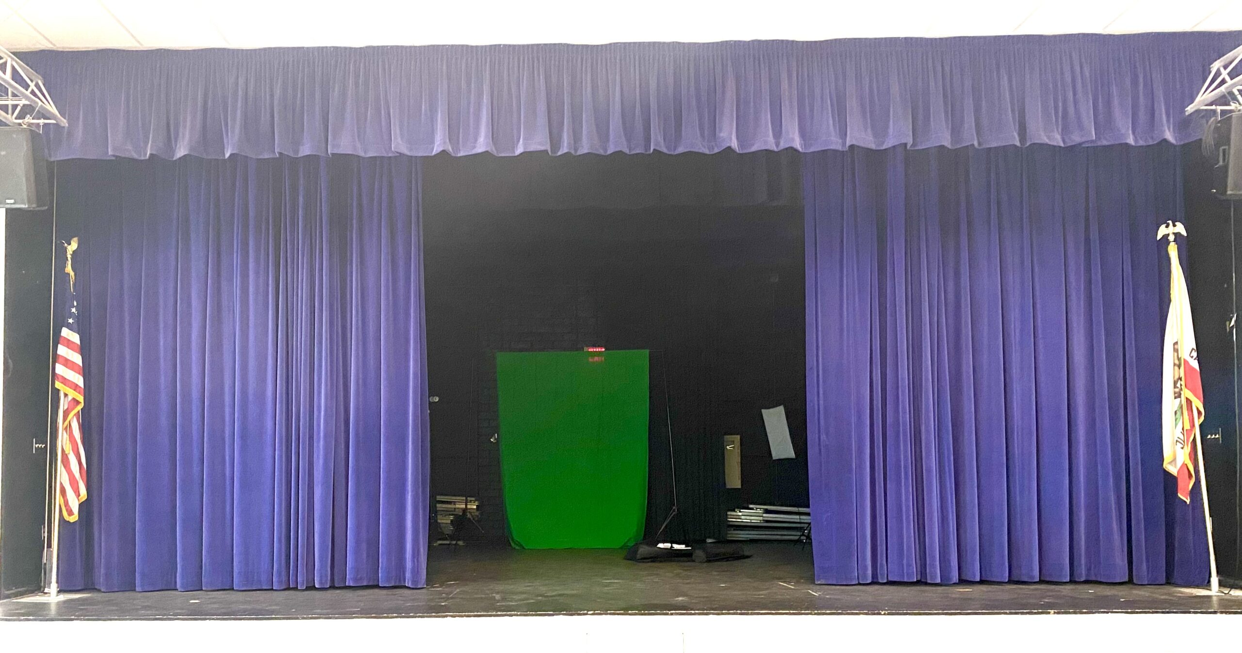 A stage with blue curtains and a green screen