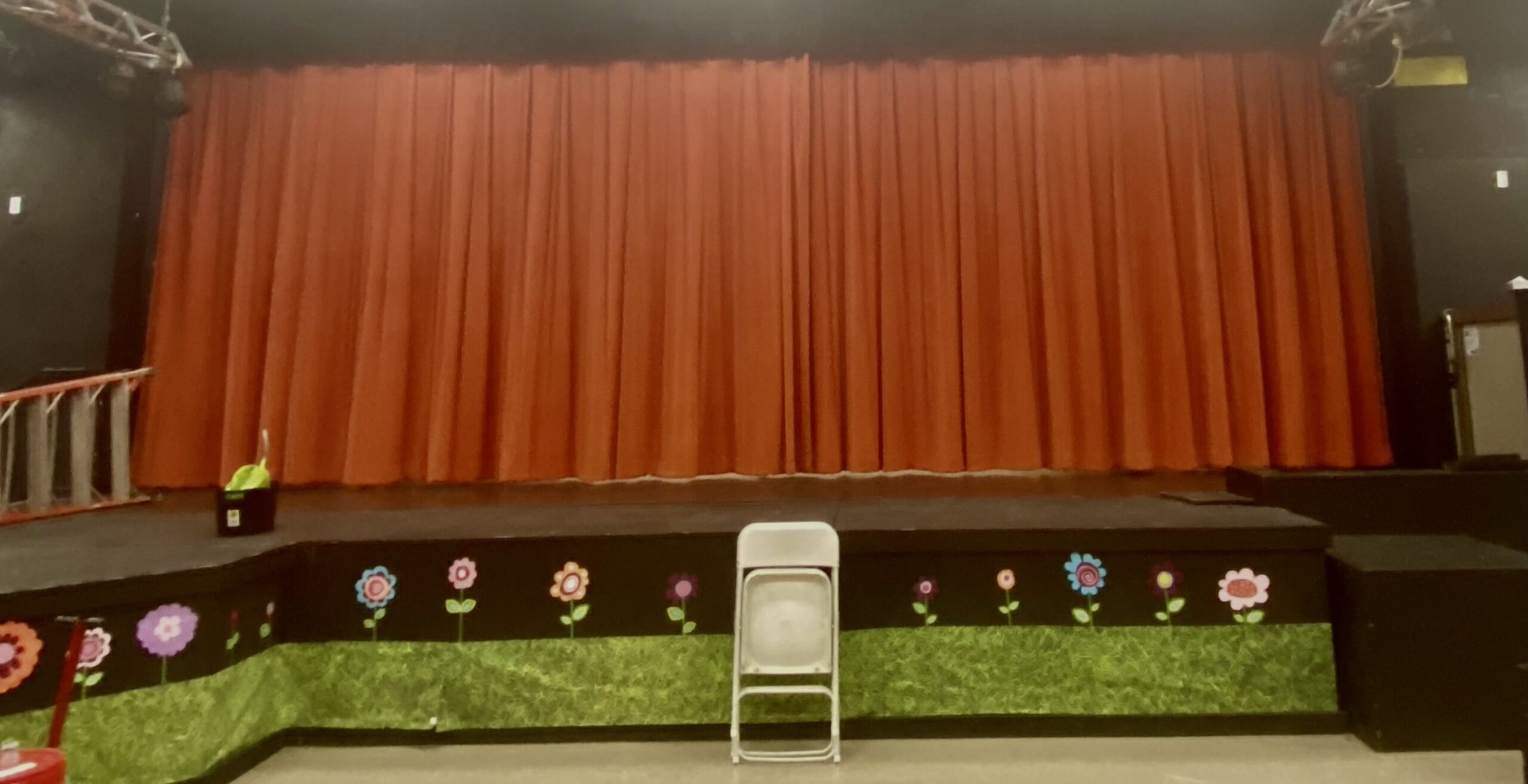 A stage with flowers and red curtains