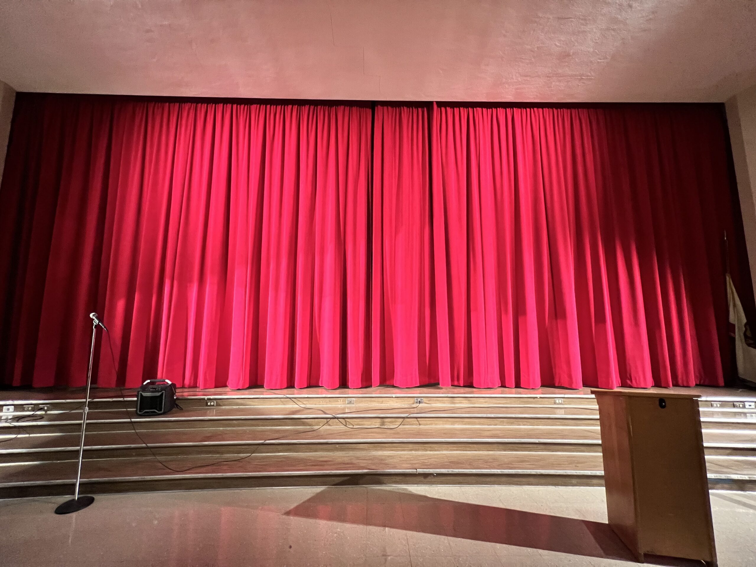 A stage with a microphone stand and red curtains